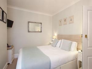 a white bedroom with a white bed and a mirror at The Castleton in Swanage