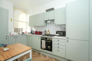 a kitchen with white cabinets and a wooden table at Sea View - Balcony - Free Parking in Ramsgate