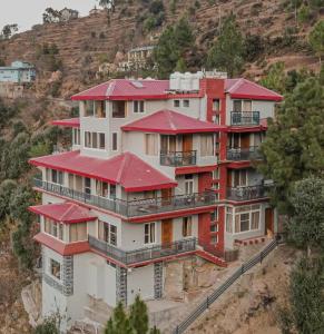 a large building with red roofs on a hill at ROSASTAYS Vatika - Mountain View in Rāmgarh