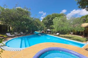 einen großen blauen Pool mit Stühlen und Bäumen in der Unterkunft Brasil Tropical Village in Pipa