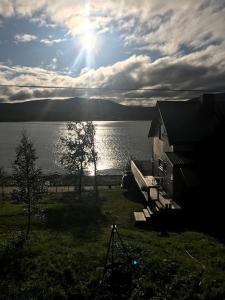 a view of a lake with a house and the sun at Trivelig fritidshus på Årnes, Senja in Straumstad