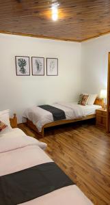 two beds in a room with wooden floors at Umda Hotel Montana in Ayubia
