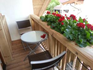 a balcony with red flowers and a table and chairs at Appartement Paratscher in Westendorf