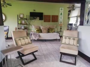 a living room with a bed and two chairs at Casa Sophia 3 listings Apartment 1 or Apartment 2 separately or Apt 1 and 2 together all with FO internet in Guápiles
