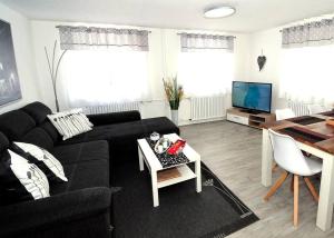 a living room with a black couch and a table at Ferienwohnung Am Steingarten beim Europa-Park in Rust