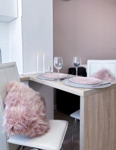 a dining room table with two glasses and a pink furry pillow at Радужная студия на Южном вокзале in Kharkiv