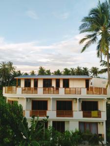 a building with a palm tree in the background at Cowry Inn in Fulidhoo