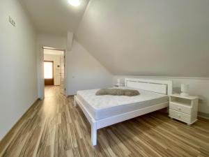 ein weißes Schlafzimmer mit einem Bett und Holzboden in der Unterkunft Жива вода in Scheschory