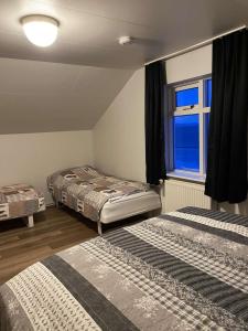 um quarto com 2 camas e uma janela em Guesthouse Básar em Grímsey
