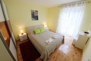 a small bedroom with a bed with two green pillows at Apartment Zubčić in Zadar