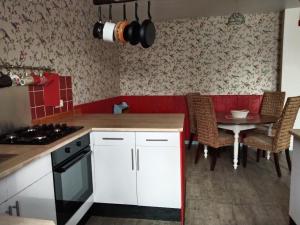 a kitchen with white cabinets and a table with chairs at Craftycotta in Glomel