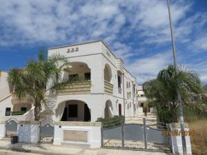 a white building with palm trees in front of it at Residence Giglio in Torre Pali