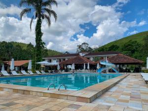a pool at a resort with a palm tree at Resort Fazenda 3 Pinheiros in Engenheiro Passos