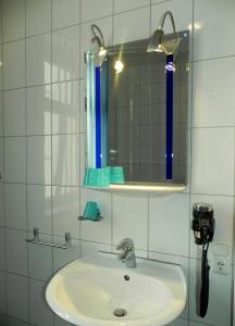 a white bathroom with a sink and a mirror at Hotel - Restaurant Braustube in Haaren