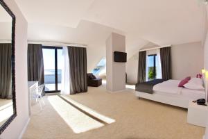 a large white bedroom with a bed and a tv at Boutique Hotel Life in Rogoznica