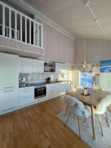a kitchen with white cabinets and a wooden table and chairs at Skarvebo - cabin with amazing view in Myro