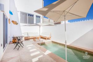 a pool with an umbrella and chairs and a table at Private Pool Condo 5-Min Drive to Waterfront Malecón! in La Paz