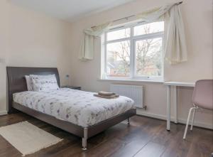 a bedroom with a bed and a window and a desk at BrumStay UK - 4 Bedrooms House with Garden, Parking and Fibre Broadband with speed upto 250mbps in Birmingham