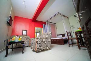 a living room with red walls and two chairs and a table at Royal Park Hotel in Jinja