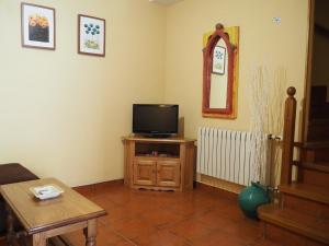 a living room with a flat screen tv and a table at Apartamentos Rurales La Escuela in Buelles