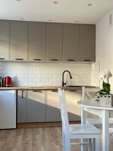 eine Küche mit grauen Schränken und einem weißen Tisch in der Unterkunft Apartament -Dwudziestka in Sandomierz