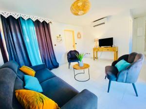 a living room with a blue couch and two chairs at Hamo Cosy in Sainte-Anne