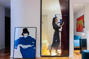 a woman standing in a room looking at a painting at Etern Stays - Boutique Apartment in Pristina