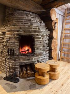 a stone fireplace in a room with benches and logs at Ruka Chalet Roma in Ruka