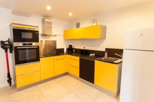 una cucina con armadi gialli e neri e frigorifero di L'escapade en baie a Abbeville