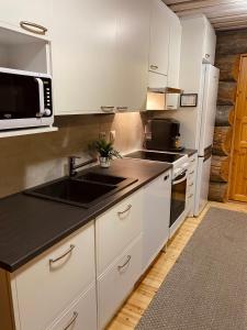 a kitchen with white cabinets and a sink and a microwave at Ruka Chalet Roma in Ruka