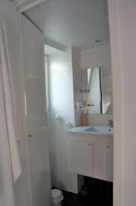 uma casa de banho branca com um lavatório e um espelho em Charmant appartement avec vue face mer imprenable em Mers-les-Bains
