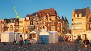 um grupo de edifícios com uma fila de cabanas de praia em Charmant appartement avec vue face mer imprenable em Mers-les-Bains