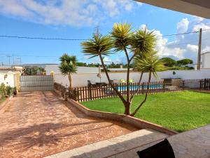 un patio con palmeras y una valla en Casa Rafael-Chalet con piscina privada, en Chiclana de la Frontera