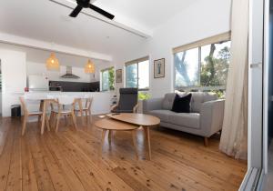 a living room and kitchen with a table and a couch at BEACHFRONT BLISS / BROULEE in Broulee
