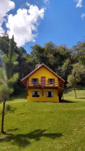 ein gelbes Haus mitten auf einem Feld in der Unterkunft Chalé Portal Lazer in Gonçalves