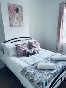 uma cama com um cobertor e almofadas em Cheerful Town House in Coventry City Centre em Coventry