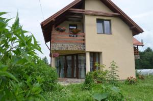 una casa con un balcón con flores. en Pensiunea Mara, en Deseşti