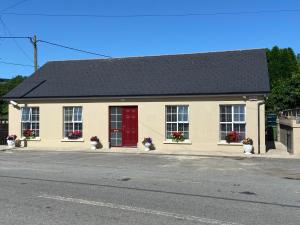 a building with a red door on a street at Duiche an Rí - Delightful Village Home in Tipperary