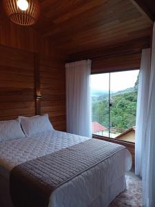 a bedroom with a bed and a large window at Recanto da Ruína in Pedra Menina