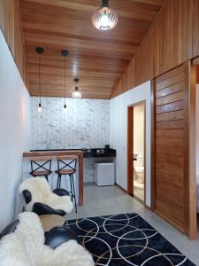 a living room with wood ceilings and a kitchen with a table at Recanto da Ruína in Pedra Menina