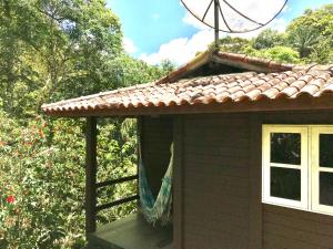 um alpendre de uma casa com uma rede de descanso em Reserva dos Manacás em São Pedro da Serra