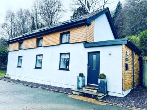 Weißes Haus mit schwarzer Tür und Fenstern in der Unterkunft Pipeline Cottage in Dolgarrog