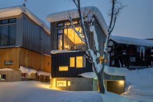 a building with a tree in the snow at Millesime - operated by H2 Life in Niseko