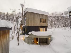 新雪谷的住宿－Millesime - operated by H2 Life，雪中的房子,有雪覆盖的树木