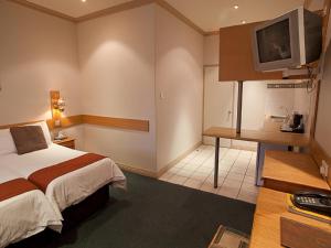 Habitación de hotel con cama y TV en Diggers Inn en Francistown