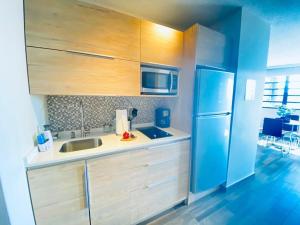 a kitchen with wooden cabinets and a blue refrigerator at KASA Starfish by the Sea - 8th floor Studio Apt for 2 BALCONY Ocean City View in San Juan