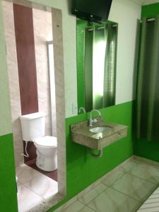 a green bathroom with a toilet and a sink at Hotel Orquídea -Rudge Ramos (Adults only) in São Bernardo do Campo