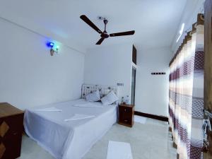 a bedroom with a white bed with a ceiling fan at Hotel Royal Beach & Restaurant in Jaliapāra