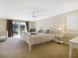 a white bedroom with a bed and a window at Camelot in Bowral