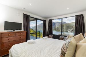 a bedroom with a bed and a large window at Okataina - Means Place of Laughter, Luxury Retreat in Queenstown
